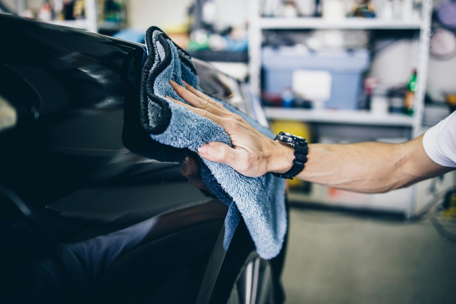Auto detailer wiping a car exterior with a microfiber towel