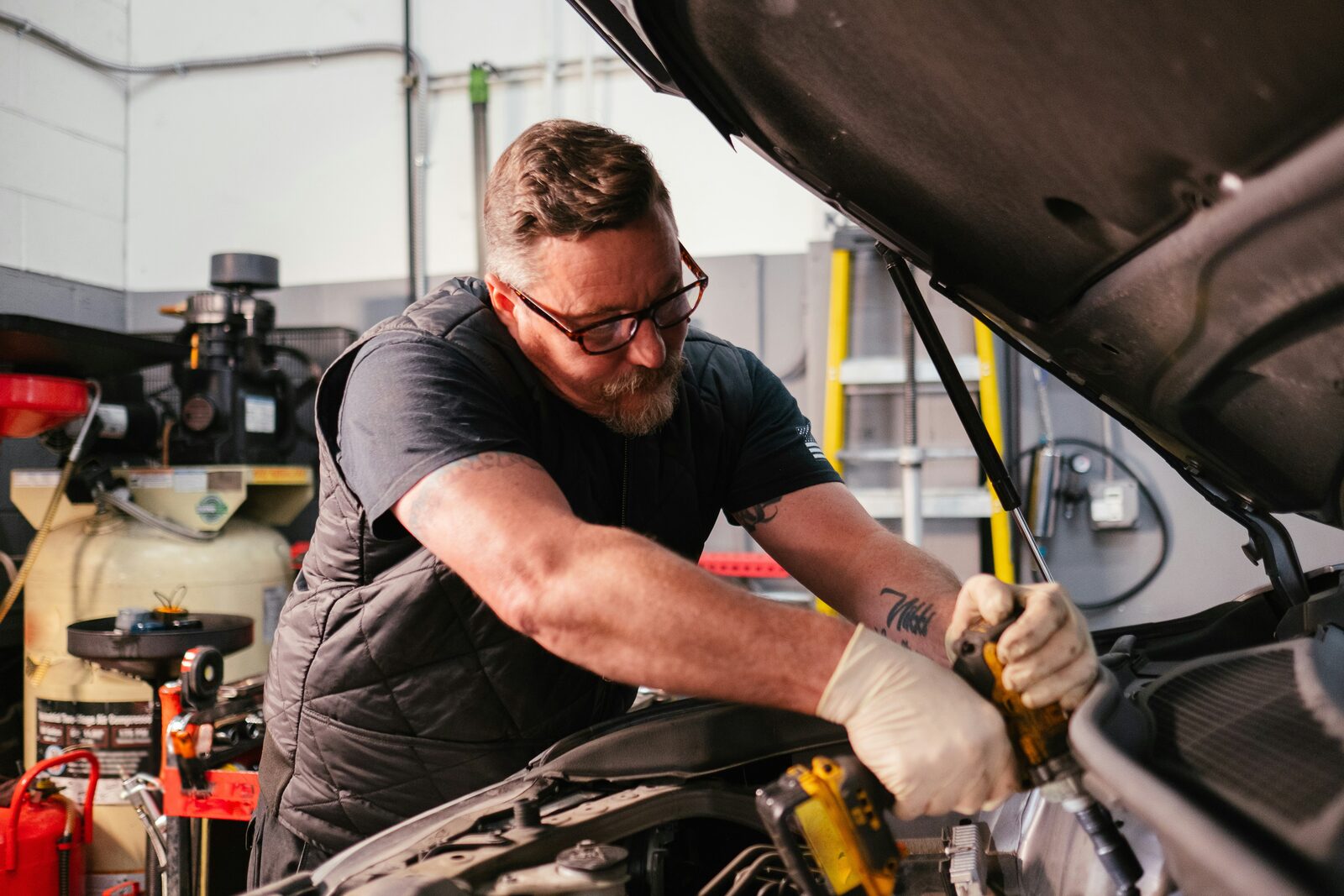 Mechanic working under the hood of a car in an auto repair shop