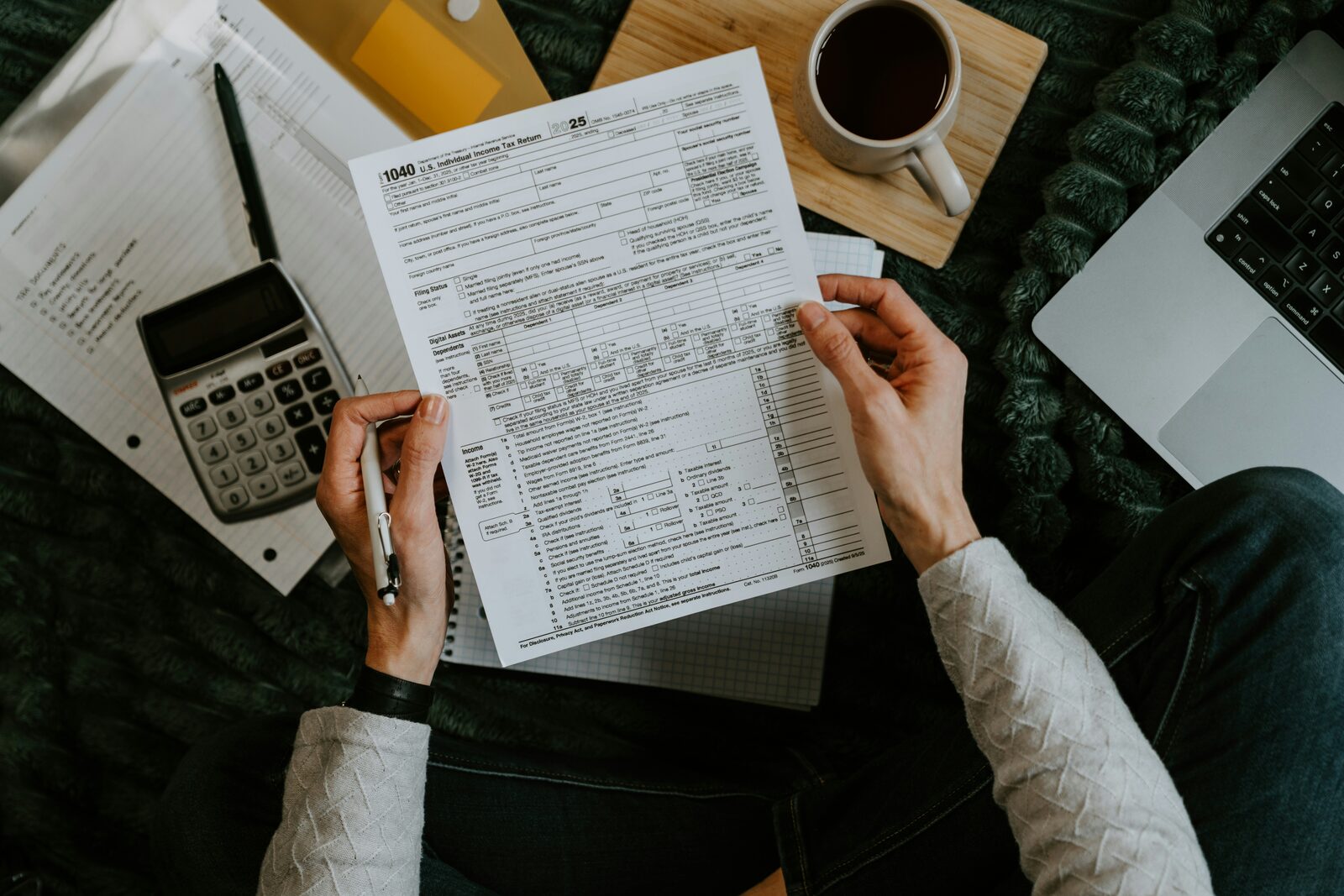 Tax paperwork being reviewed beside a calculator and laptop