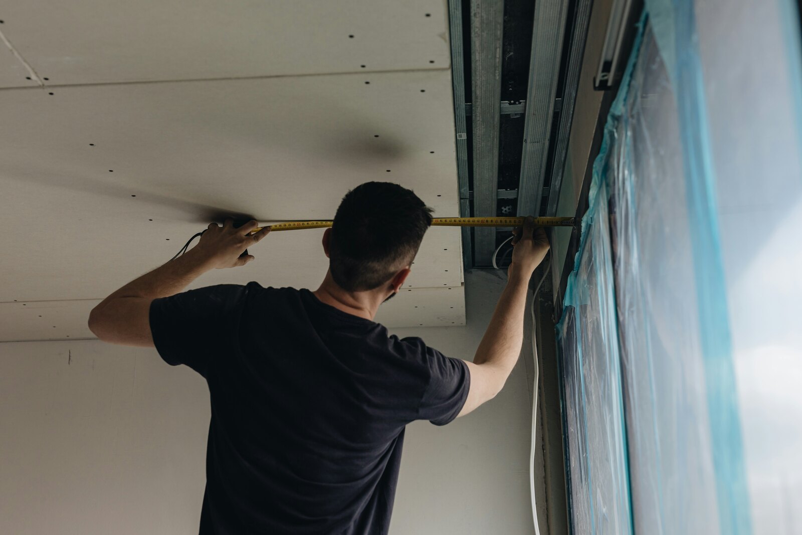 Worker measuring beside the overhead track of a garage door