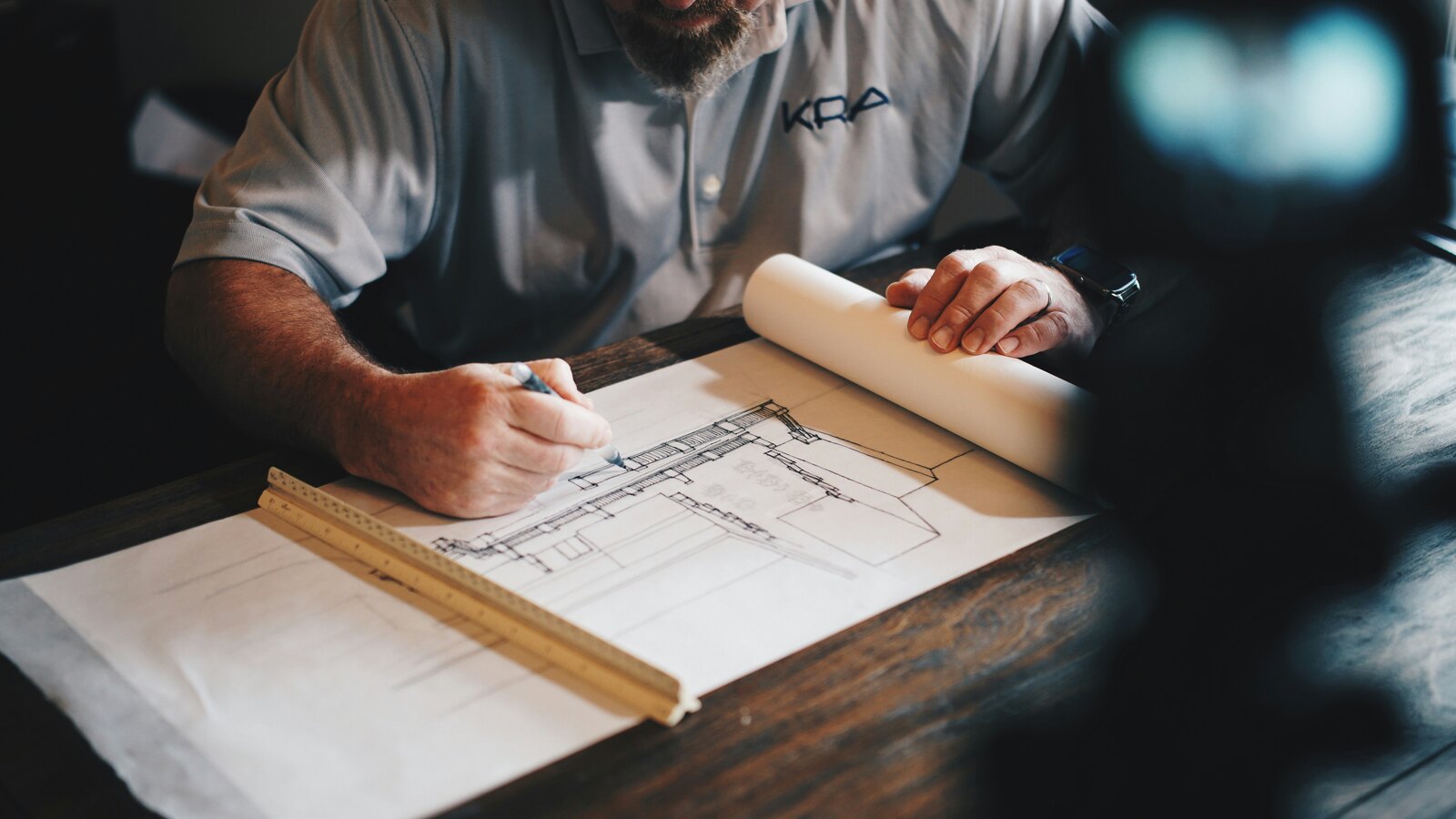 Professional reviewing and marking a building floor plan at a desk