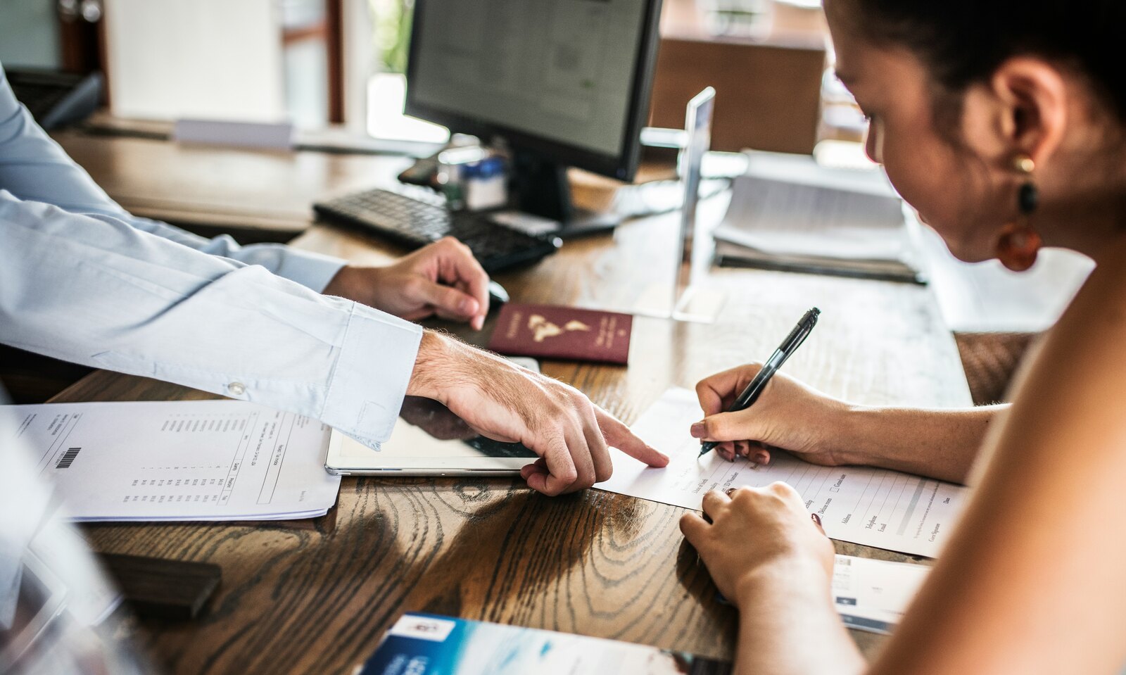 People reviewing and signing paperwork together at a desk