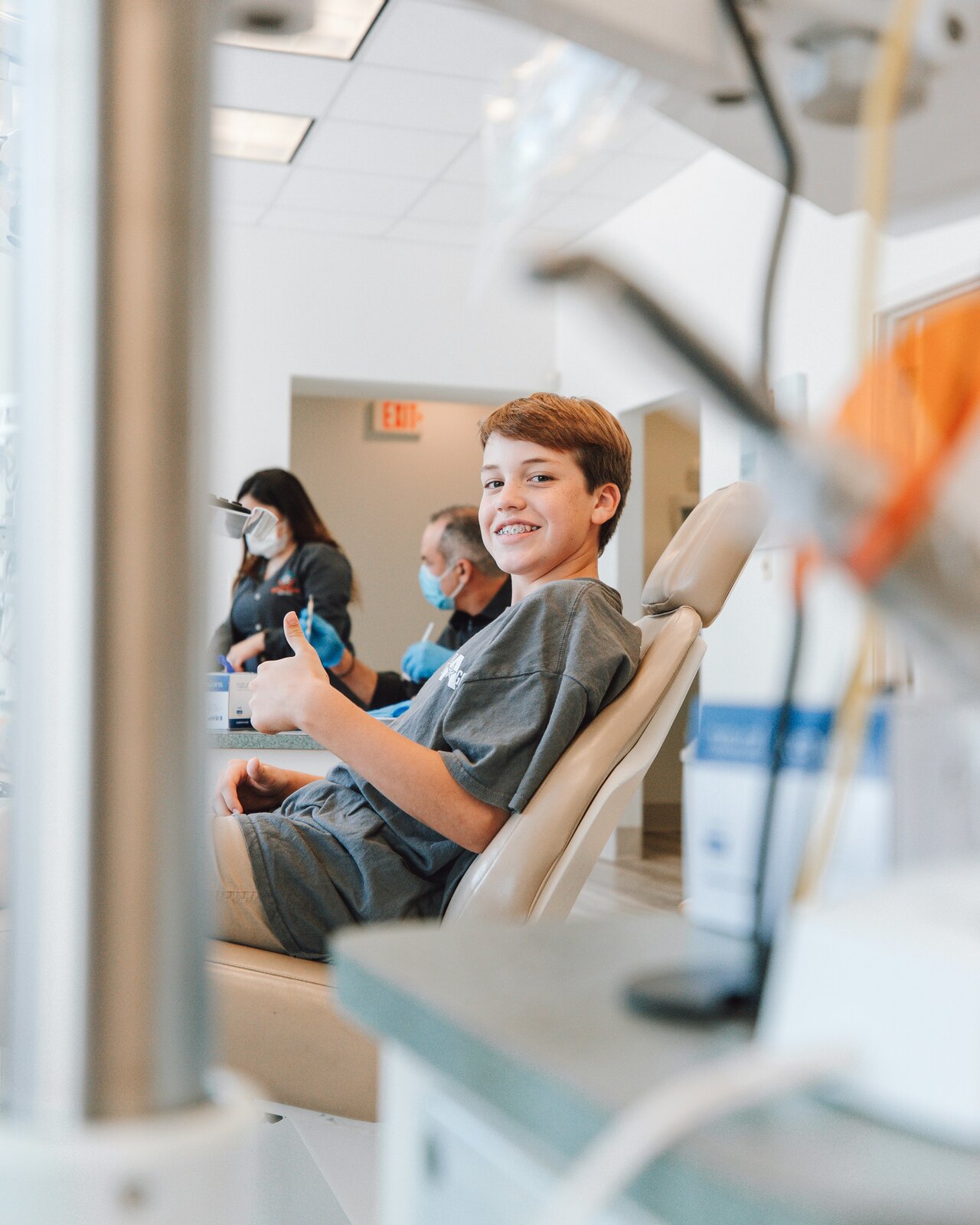 Person seated in a dental chair with dental staff in the background