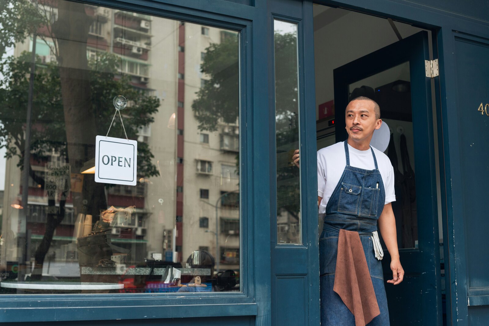 Restaurant worker wearing an apron in an open restaurant doorway