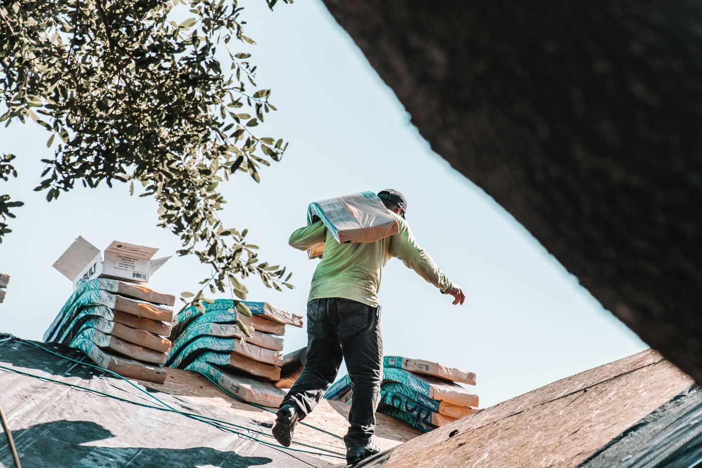 Roofing worker carrying materials across a roof under repair